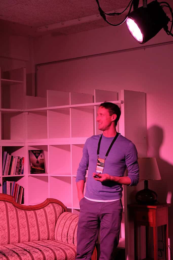 A man speaking confidently at the Coffeehouse Conference, illuminated by pink stage lighting.