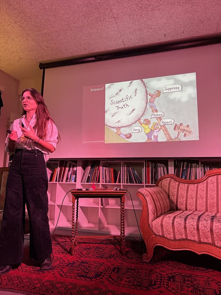 Woman presenting on scientific debate and truth at Coffeehouse Conference event.