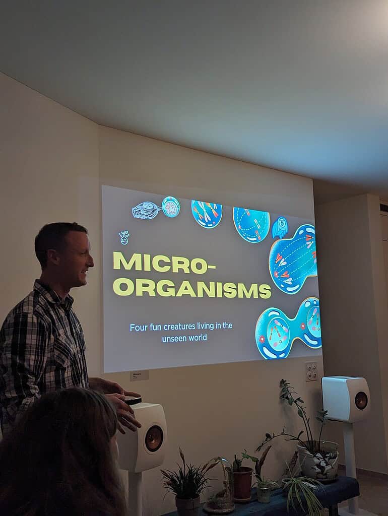 Speaker presenting on micro-organisms and their role in the unseen world at Coffeehouse Conference.