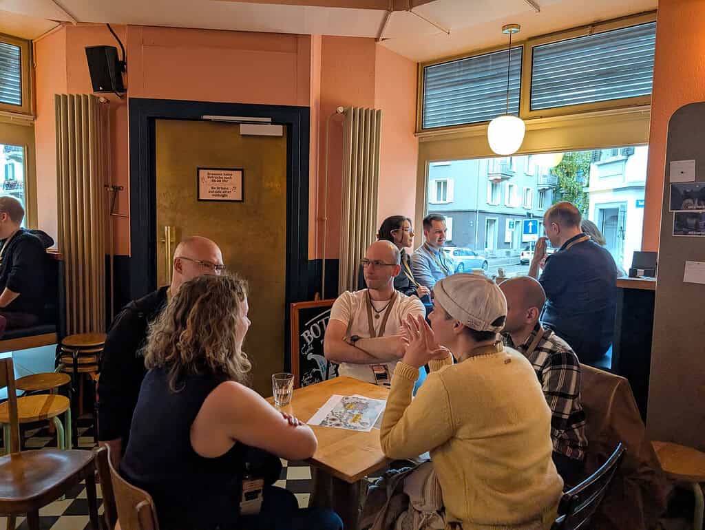 People engaged in lively discussion at Coffeehouse Conference in a cafe.