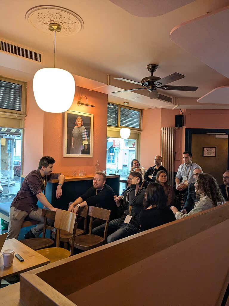 People engaging in a discussion at the Coffeehouse Conference event in a cozy, well-lit cafe.